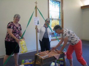 Lisa, Pastor Judy, and Cathy prepare our Diaper Christmas Tree